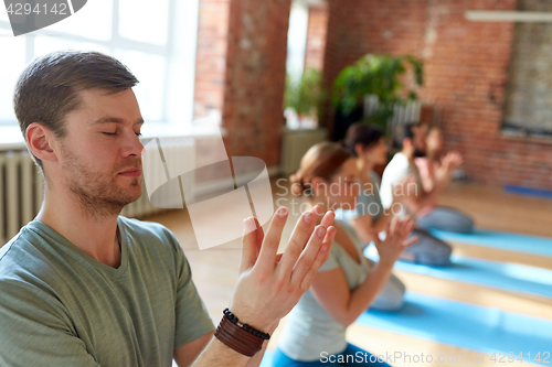 Image of man with group of people meditating at yoga studio