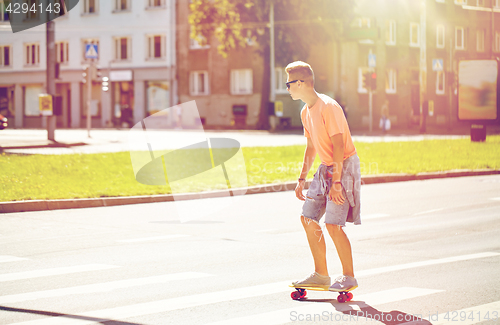 Image of teenage boy on skateboard crossing city crosswalk