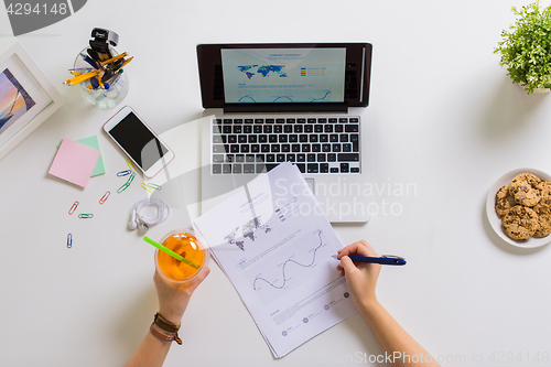 Image of hands with laptop and papers at office table