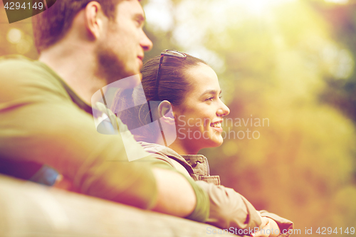 Image of smiling couple with backpacks on bridge in nature