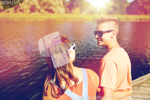 Image of happy teenage couple sitting on river berth