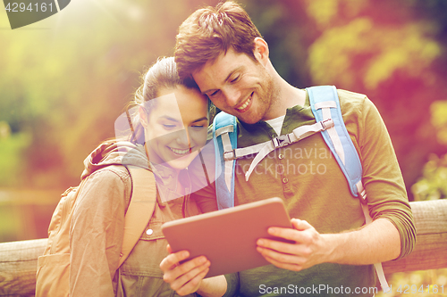 Image of happy couple with backpacks and tablet pc outdoors