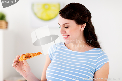 Image of happy woman eating pizza at home kitchen