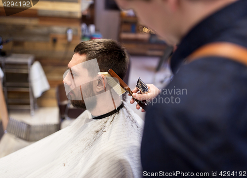 Image of man and barber with brush cleaning hair at salon