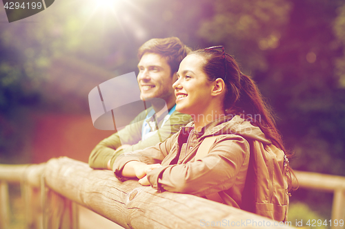 Image of smiling couple with backpacks on bridge in nature