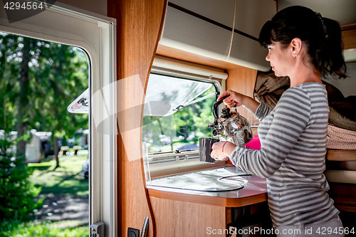 Image of Woman cooking in camper, motorhome interior