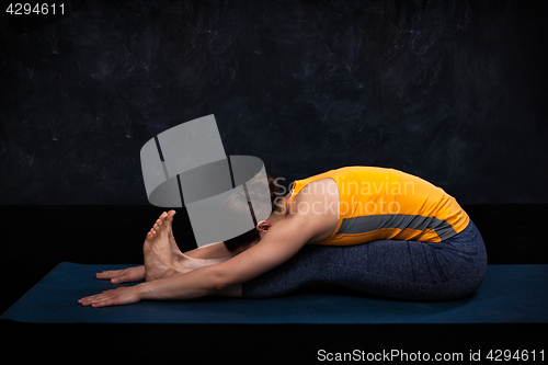 Image of Woman practices Ashtanga Vinyasa yoga asana Paschimottanasana