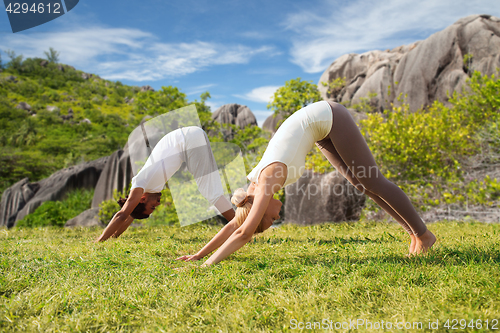 Image of smiling couple making yoga exercises outdoors