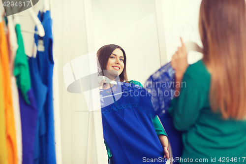 Image of happy woman choosing clothes at home wardrobe