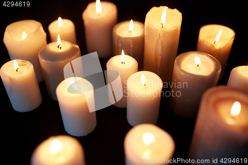 Image of candles burning in darkness over black background