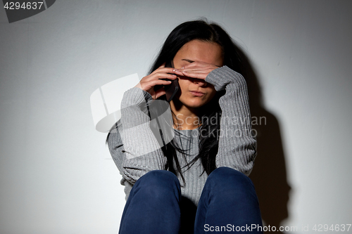 Image of unhappy woman crying and calling on smartphone