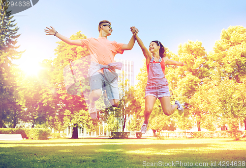 Image of happy teenage couple jumping at summer park