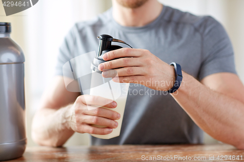 Image of close up of man with protein shake bottle and jar