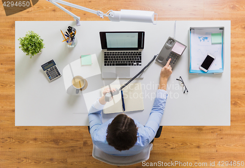 Image of businesswoman calling on phone at office table