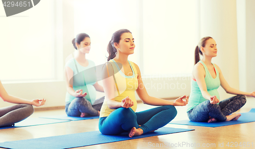 Image of happy pregnant women exercising yoga in gym