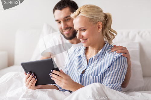 Image of smiling happy couple with tablet pc in bed at home