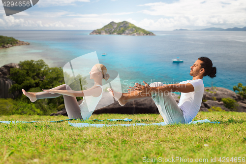 Image of couple making yoga half-boat pose outdoors