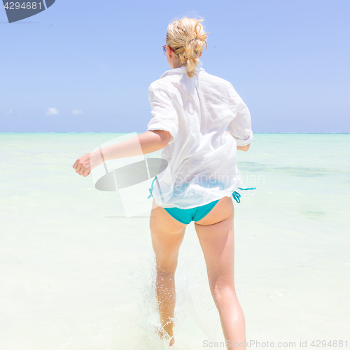 Image of Young active woman having fun running and splashing in shellow sea water.