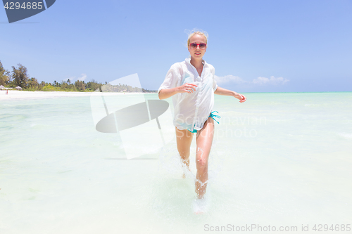 Image of Young active woman having fun running and splashing in shellow sea water.