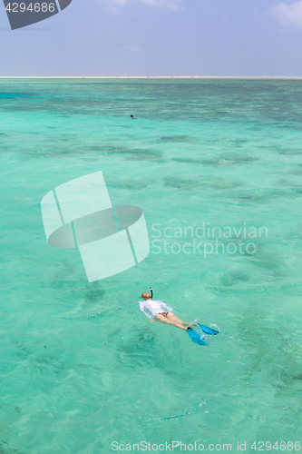 Image of Woman snorkeling in clear shallow sea of tropical lagoon with turquoise blue water.