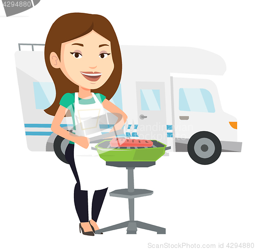 Image of Woman having barbecue in front of camper van.