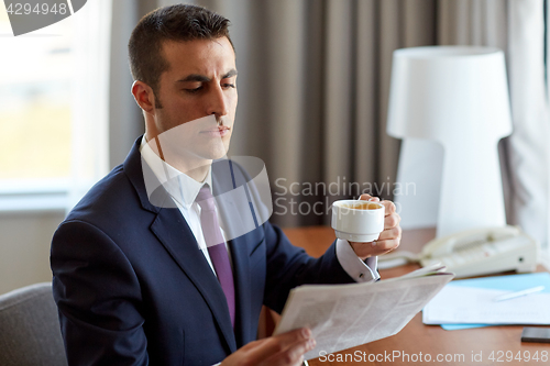 Image of businessman reading newspaper and drinking coffee