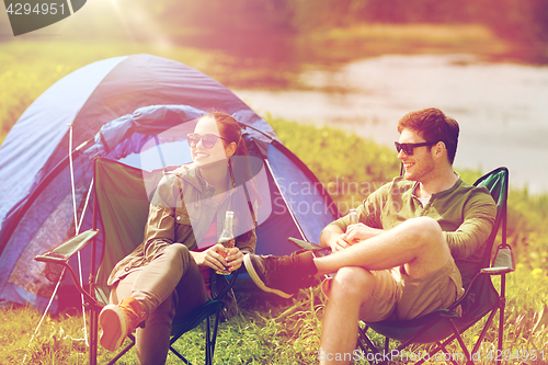 Image of happy couple drinking beer at campsite tent