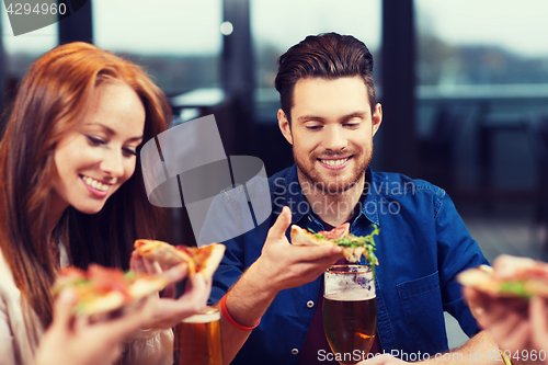 Image of friends eating pizza with beer at restaurant