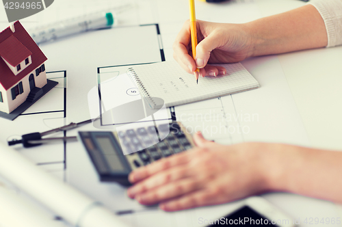 Image of close up of hand on blueprint writing to notebook