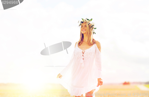 Image of happy young woman in flower wreath on cereal field