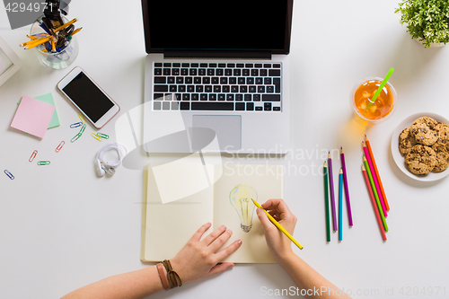 Image of woman hands drawing in notebook at home office