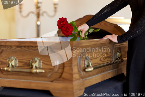 Image of woman with red roses and coffin at funeral