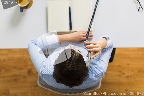 Image of businesswoman calling on phone at office table