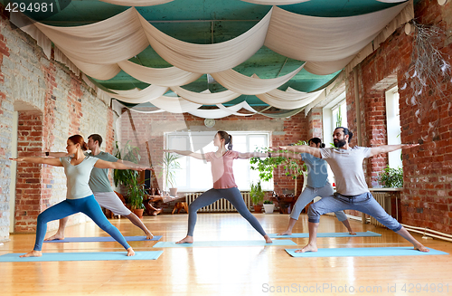 Image of group of people doing yoga warrior pose at studio