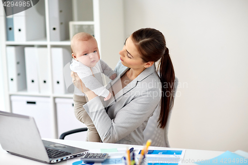 Image of happy businesswoman with baby and laptop at office