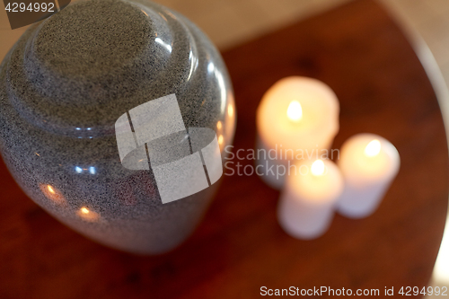 Image of cremation urn and candles burning on table