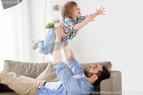 Image of happy young father playing with little son at home