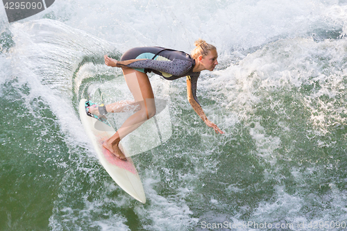 Image of Atractive sporty girl surfing on famous artificial river wave in Englischer garten, Munich, Germany.