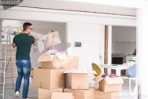 Image of couple carrying a carpet moving in to new home