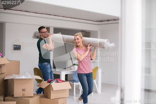 Image of couple carrying a carpet moving in to new home