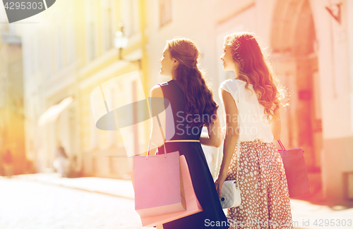 Image of happy women with shopping bags walking in city 