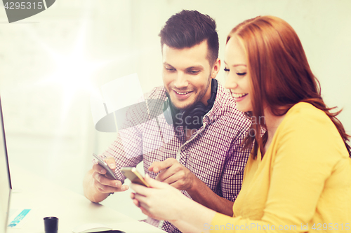 Image of smiling creative team with smartphones at office