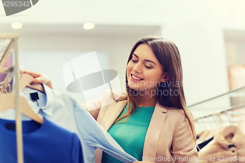 Image of happy young woman choosing clothes in mall