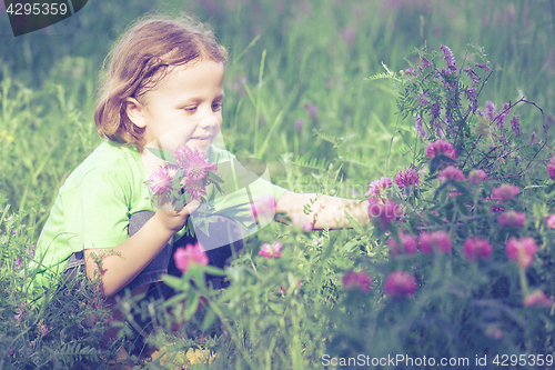 Image of Cute little boy  playing with flowers in  park
