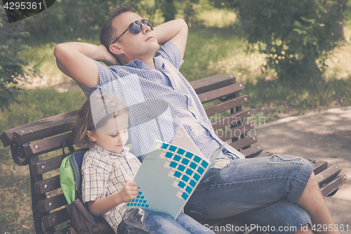 Image of Father and son playing at the park on bench at the day time.