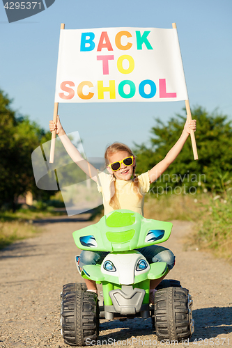 Image of Happy little girl playing on road at the day time. He driving on