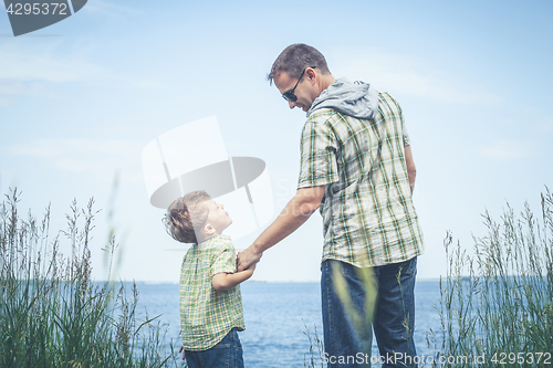 Image of Father and son playing at the park near lake at the day time.