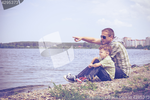 Image of Father and son playing at the park near lake at the day time.