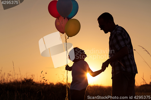 Image of Father and son playing at the park at the sunset time.