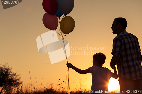 Image of Father and son playing at the park at the sunset time.